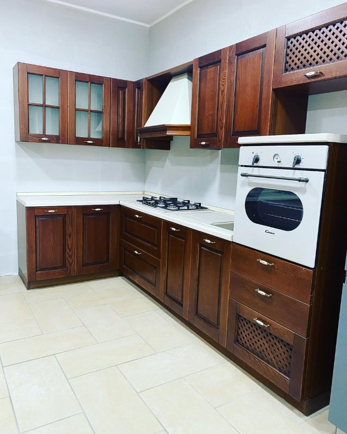 Cucina classica ad angolo in legno scuro con ante a telaio e vetrine, realizzata su misura da Centro Cucine